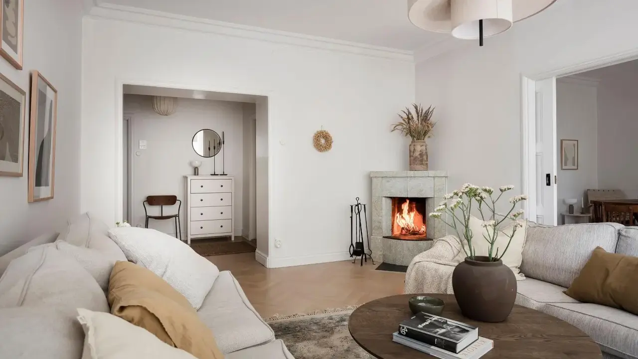 Accogliente soggiorno con camino acceso, divani chiari e un tavolino in legno. Idee per la casa e la campagna.