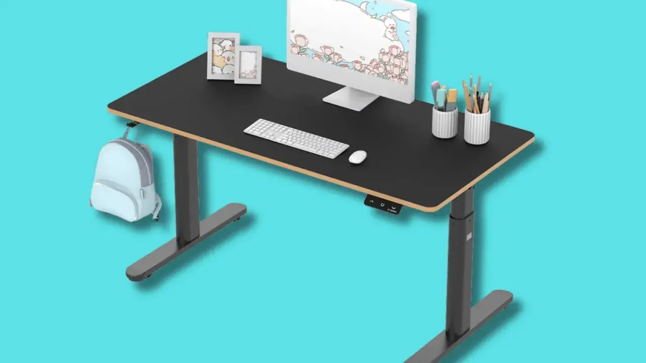 Tavolino gaming nero regolabile in altezza, con monitor, tastiera, mouse, porta penne e zainetto azzurro appeso.