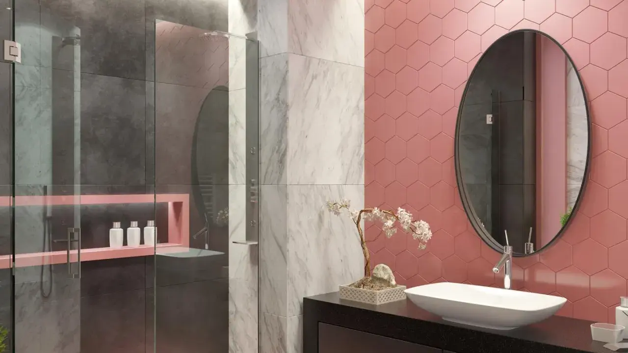 Bagno moderno con pareti rosa a nido d'ape, doccia grigia e marmo. Un lavabo ovale su mobile nero e specchio rotondo completano queste idee bagno rosa.