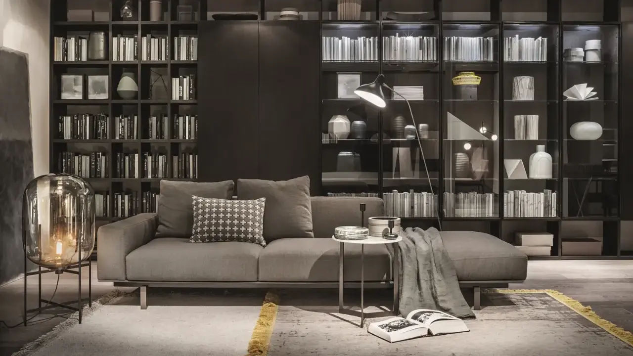 Elegante soggiorno con divano grigio, tavolino e una maestosa lema parete attrezzata piena di libri e oggetti decorativi.