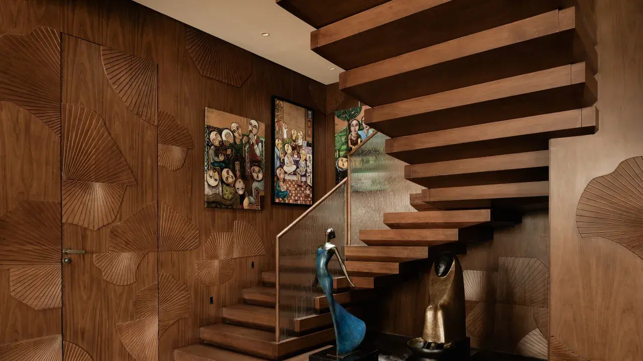Elegante interior design casa con pareti in legno intagliato a ventaglio, quadri astratti e una scala sospesa in legno.