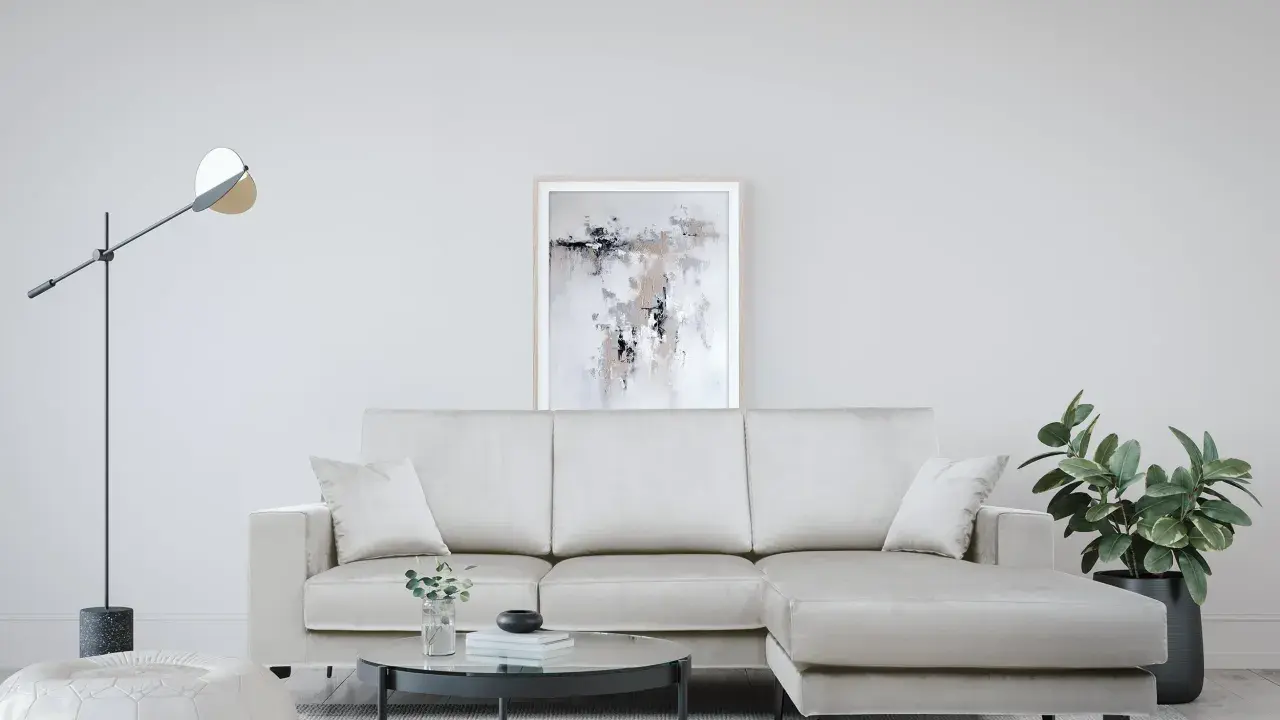 Divano angolare color crema, con tavolino rotondo in vetro e pouf bianco. Le misure del divano angolare sono perfette per questo spazio.