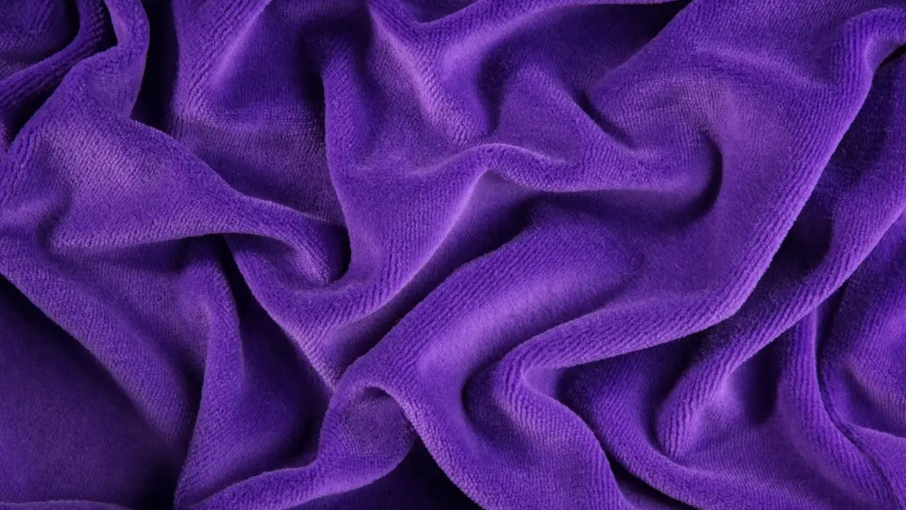 Tessuto di velluto viola drappeggiato, morbido e lussuoso. Scopri come lavare il velluto per mantenerlo splendente.