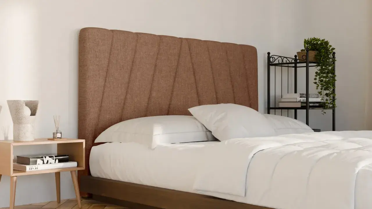 Un letto in tessuto marrone con testiera imbottita, lenzuola bianche e comodino in legno. Ideale per chi cerca consigli su come pulire letto in tessuto.