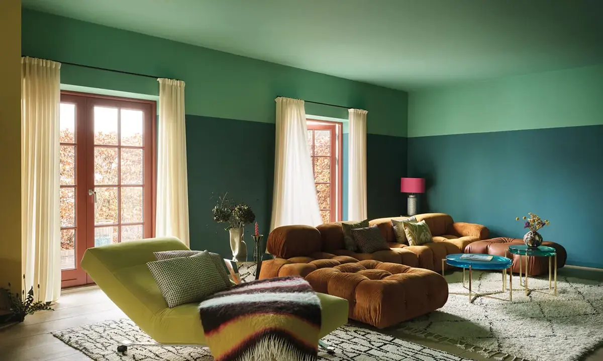 Divano arancione e chaise longue verde menta in un soggiorno moderno con pareti bicolore.
