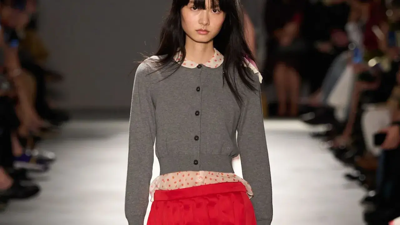 Modella con cardigan grigio e gonna rosso vivo, un contrasto audace.