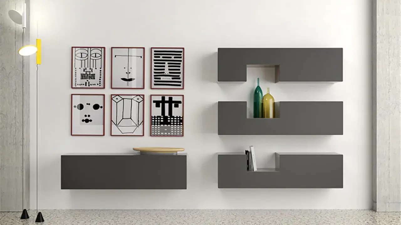 Parete con sei stampe astratte, mensole **Minottitalia** grigie con bottiglie e libri, lampada da terra.