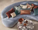 Tante idee cuscini divano: tonalità calde e fredde, fantasie geometriche e texture vellutate su un divano grigio.