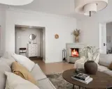 Accogliente soggiorno con camino acceso, divani chiari e un tavolino in legno. Idee per la casa e la campagna.