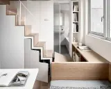 Monolocale con soppalco: scala in legno e bianco, bagno con doccia, scrivania e letto integrati.