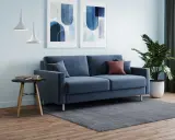 Soggiorno moderno con divano blu, quadri astratti e piante. L'altezza mensole sopra divano è ideale per l'arredo.