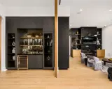 Elegante angolo bar in casa con bottiglie, cantinetta e mensole a vista.