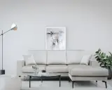 Divano angolare color crema, con tavolino rotondo in vetro e pouf bianco. Le misure del divano angolare sono perfette per questo spazio.