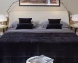 Un letto ben fatto, con copriletto trapuntato scuro e cuscini coordinati. Un esempio di come rifare il letto per un'atmosfera elegante.