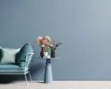 Divano blu e un tavolino con fiori su una parete azzurra, un'idea per pareti colorate particolari che crea un'atmosfera rilassante.