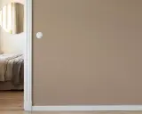 Camera da letto con letto accogliente, specchio rotondo e pareti color taupe.