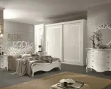 Elegante camera da letto bianca con letto capitonné, armadio scorrevole e comò con specchio. Ottime idee camera da letto bianca per un ambiente raffinato.