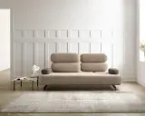 Un elegante divano beige, un'opera d'arte di design, domina la scena. Accanto, un tavolino con libri e una scultura moderna.