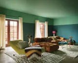 Divano arancione e chaise longue verde menta in un soggiorno moderno con pareti bicolore.