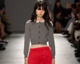 Modella con cardigan grigio e gonna rosso vivo, un contrasto audace.