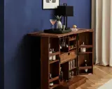 Elegante mobile bar design in legno scuro, aperto, con bottiglie, bicchieri, lampada e decorazioni.
