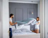 Coppia felice cambia le lenzuola, un promemoria su ogni quanto cambiare le lenzuola per un sonno fresco e igienico.