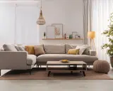 Divano angolare color taupe, con cuscini decorativi, tavolino in legno e pianta verde.