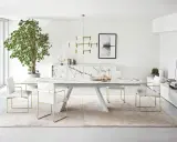 Un elegante soggiorno con un tavolo Calligaris in marmo, sedie bianche con dettagli dorati e un grande albero verde.