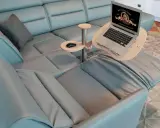 Comodo tavolino porta pc in legno e metallo, agganciato a un divano in pelle azzurra, con laptop aperto e mouse.