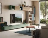 Un moderno salotto con tv al centro, mensole a muro, libreria e divano, con vista su un giardino lussureggiante.