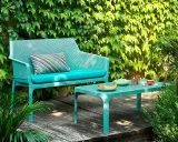 Divano e tavolino Nardi Spa Chiampo in un giardino rigoglioso, con cuscini color acqua e un set da tè.