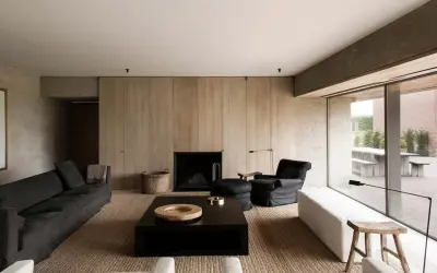 Elegante salone moderno con divani scuri, camino a parete in legno, tavolino nero e poltrona. Un esempio di come arredare un salone con stile minimalista.