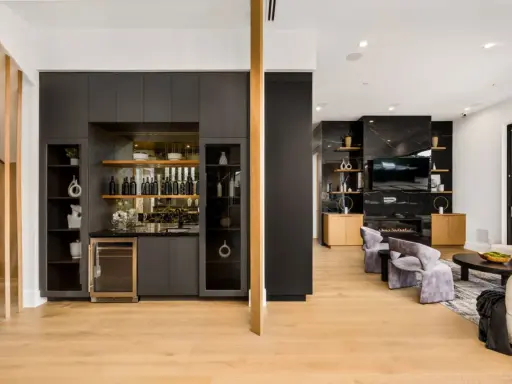 Elegante angolo bar in casa con bottiglie, cantinetta e mensole a vista.
