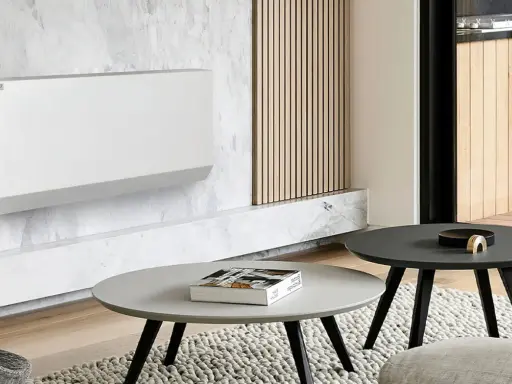 Un moderno termosifone bianco su parete in marmo, un'idea per arredare parete con termosifone in modo elegante. Tavolini e tappeto completano l'arredo.
