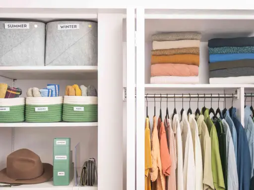Closet with organized shelves: labeled bins for scarves, gloves, hats, jewelry, bandanas, belts, stacked sweaters, and hanging clothes.