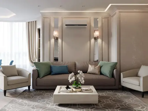 Un salotto con un divano marrone, due poltrone beige e un tavolino bianco. L'arredamento contemporaneo chic è completato da cuscini verdi e blu, un tappeto geometrico e luci soffuse.