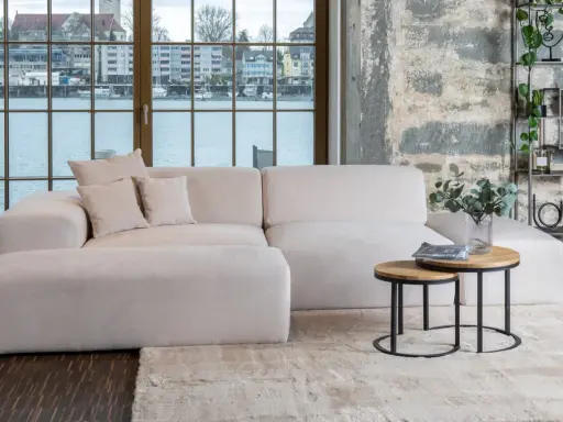 Un tavolino rotondo in legno e metallo con riviste e un vaso di eucalipto: idee per cosa mettere sul tavolino del salotto.