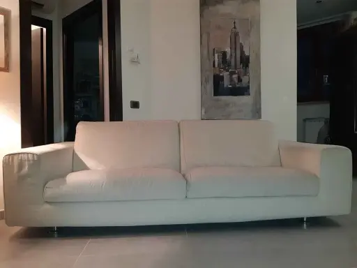 Un comodo divano bianco, perfetto per rilassarsi, con un quadro di New York alle spalle. I divani Bosal sono sinonimo di comfort.