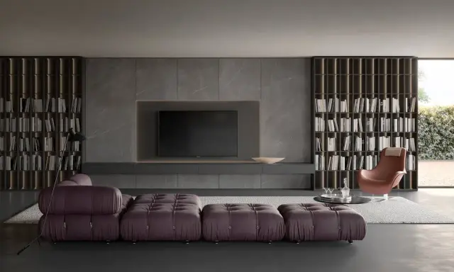 Elegante soggiorno con un moderno tv design integrato in una parete in marmo, librerie a tutta altezza e divano componibile viola.