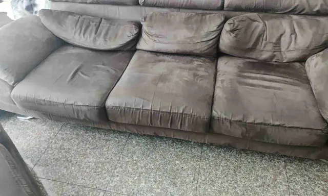 Divano marrone con cuscini un po' affossati, pronti per rifare imbottitura cuscini divano e ridargli vita.
