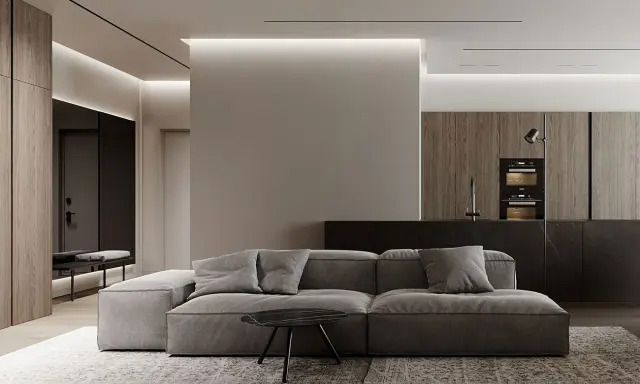 Soggiorno moderno con divano grigio, tavolino nero e cucina a vista. Un pilastro centrale, illuminato da luci a led, offre spunti su come abbellire un pilastro in soggiorno.