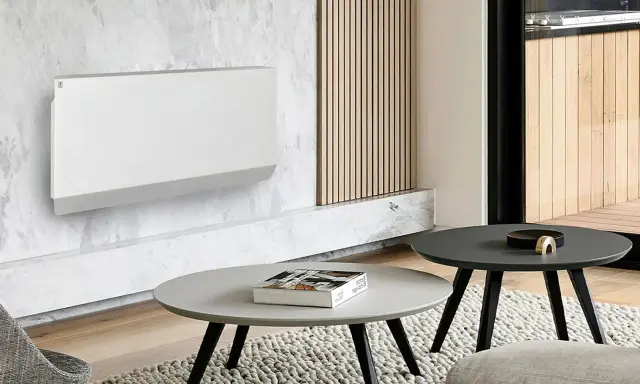 Un moderno termosifone bianco su parete in marmo, un'idea per arredare parete con termosifone in modo elegante. Tavolini e tappeto completano l'arredo.