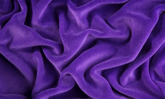 Tessuto di velluto viola drappeggiato, morbido e lussuoso. Scopri come lavare il velluto per mantenerlo splendente.