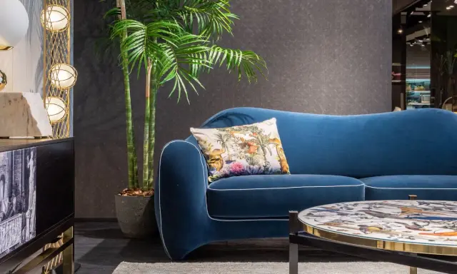 Divano blu petrolio con cuscino decorato. Abbinamenti eleganti con tavolino e arredi moderni.