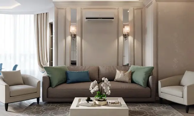 Un salotto con un divano marrone, due poltrone beige e un tavolino bianco. L'arredamento contemporaneo chic è completato da cuscini verdi e blu, un tappeto geometrico e luci soffuse.