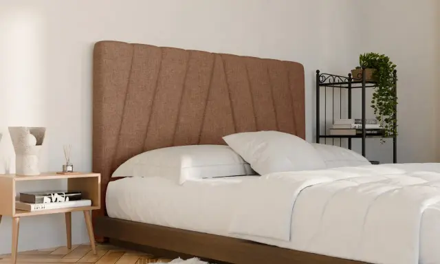 Un letto in tessuto marrone con testiera imbottita, lenzuola bianche e comodino in legno. Ideale per chi cerca consigli su come pulire letto in tessuto.