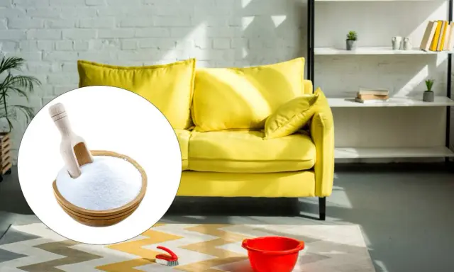 Un divano giallo brillante pronto per essere pulito con bicarbonato. Una ciotola di bicarbonato con un mestolo è in primo piano.