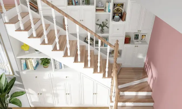 Soluzione creativa per arredare sottoscala a vista: librerie bianche e contenitori su misura sfruttano ogni centimetro, integrandosi con la scala in legno.