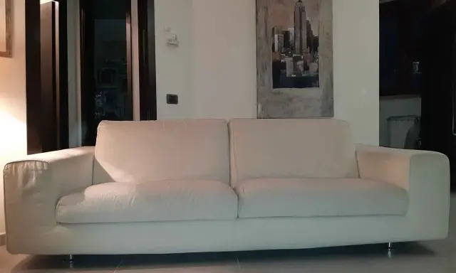 Un comodo divano bianco, perfetto per rilassarsi, con un quadro di New York alle spalle. I divani Bosal sono sinonimo di comfort.