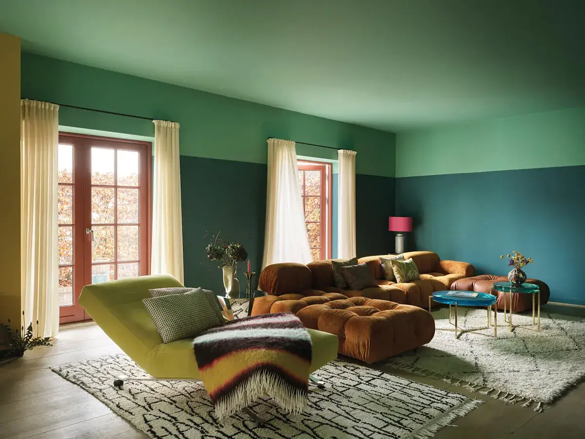 Divano arancione e chaise longue verde menta in un soggiorno moderno con pareti bicolore.